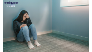 online therapy 13 A woman sitting on the floor with her head in her hands, showing signs of burnout, fatigue, and the mental health challenges many adults face in balancing work, life, and personal well-being.