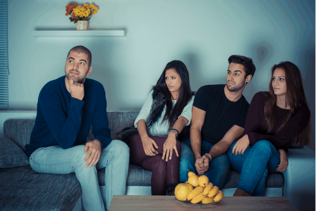A group of friends sitting on a couch, but one of them is being judged by the rest, which could lead to some social anxiety.