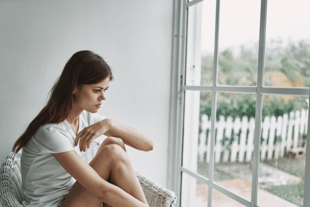 A woman sits at home alone, avoiding going out and facing social situations.