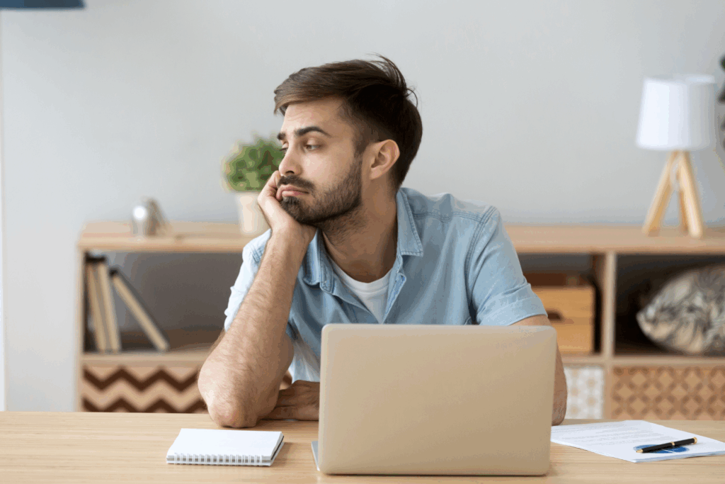 A man sits at his laptop, distracted and worrying about an upcoming social event.
