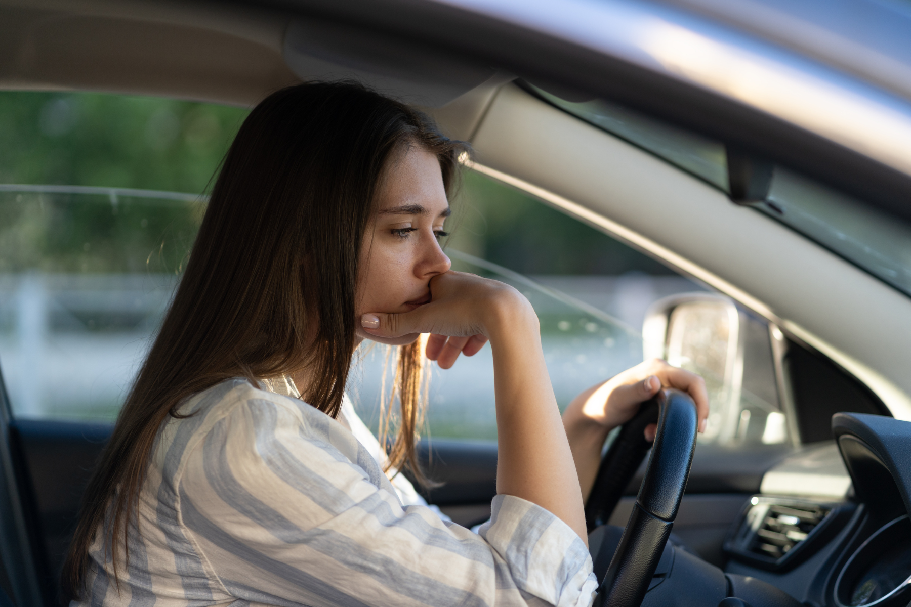 A woman suffering from social anxiety sits in her car.